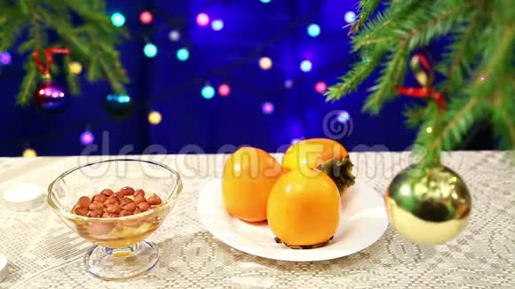 柿子坚果和蜂蜜在桌子上有一棵装饰的圣诞树和闪烁的动名词模糊的视频的预览图