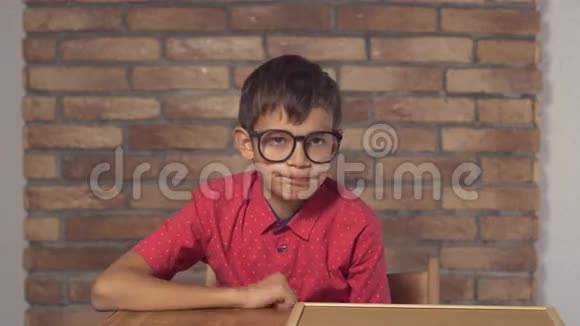 坐在书桌前的孩子拿着一张挂图背景是红砖墙上的刻字出售视频的预览图