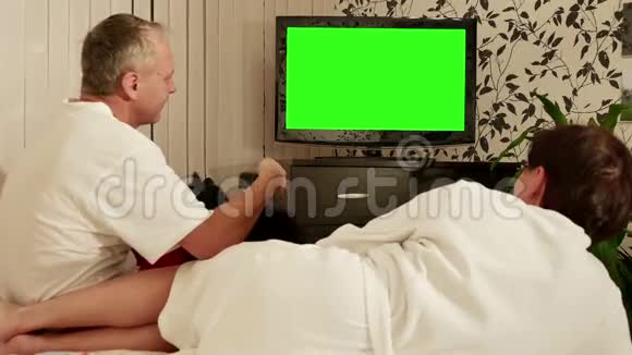 一对夫妇坐在沙发上用绿色屏幕看电视视频的预览图