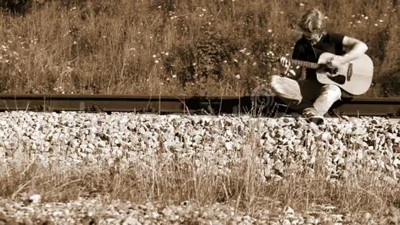 一位左撇子长发吉他手坐在铁路上演奏视频的预览图