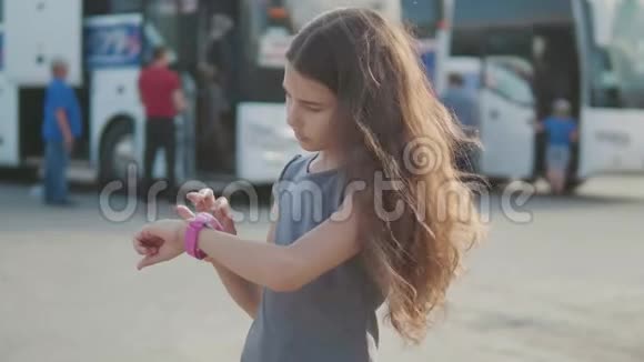 小女孩在智能互联网时钟社交媒体上看慢动作视频公共汽车站的少女离开视频的预览图