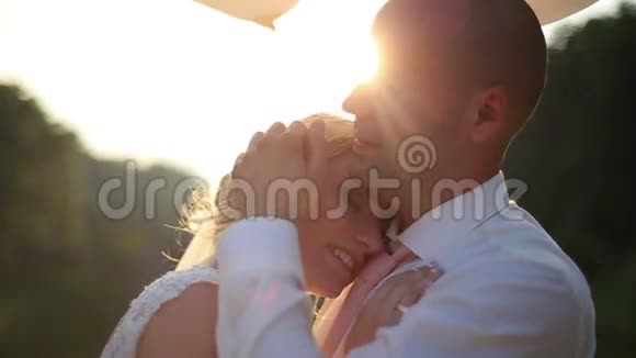 时刻的温柔新婚夫妇在婚礼当天轻轻地拥抱在桥上夏日夕阳背景视频的预览图