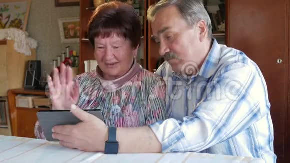 一对老年夫妇通过连接平板电脑的视频与他们的孙子进行交流一男一女在和视频的预览图