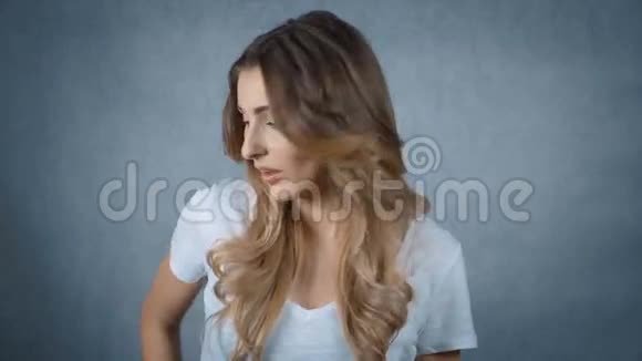 开朗的年轻女人拿着手机在灰色的背景下微笑视频的预览图