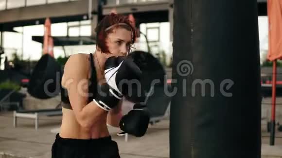 漂亮的运动女拳击手戴手套打拳击袋在外面健身女子拳击训练视频的预览图