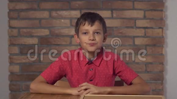坐在书桌前的孩子拿着挂图背景是红砖墙上刻着字母的出租车视频的预览图