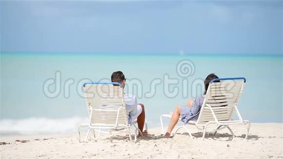 快乐的一对情侣在日光浴的热带海滩上放松视频的预览图
