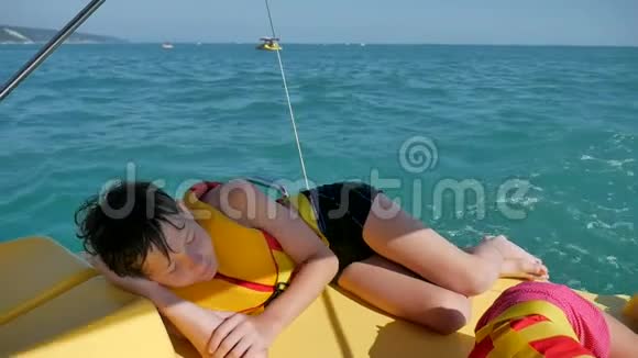 少年睡在海上的船上一个十几岁的男孩在一艘游艇上休息双体船在海洋中的水上视频的预览图