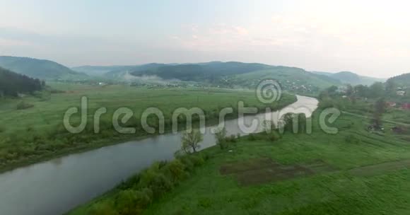在一个丘陵的山谷里飞过河流空中景观视频的预览图