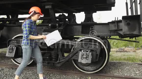 一个年轻的女火车司机检查货车的车轴箱视频的预览图