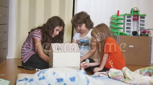 可爱的小女孩在玩玩具孩子们用手在室内制作了纸盒娃娃屋视频的预览图