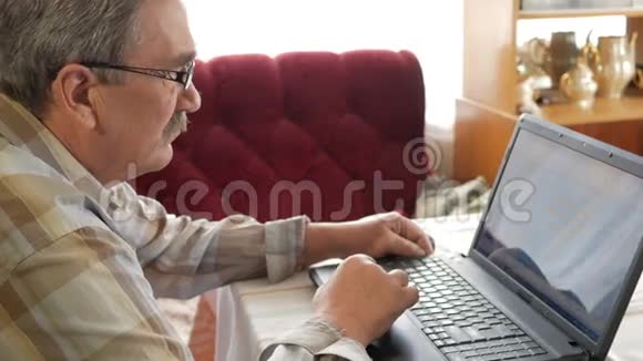 戴眼镜的老人为笔记本电脑工作他认真地看着班长视频的预览图