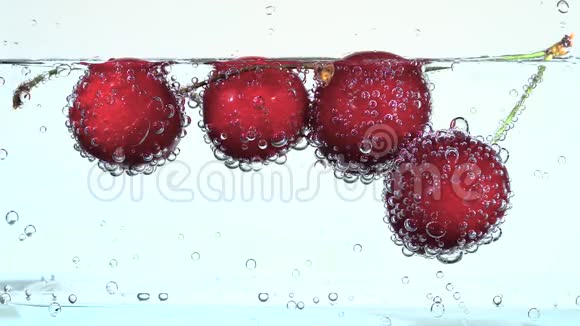 红樱桃在气泡中漂浮在清澈的水中视频的预览图