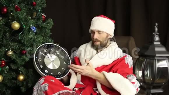 坏残暴的圣诞老人微笑着在圣诞树的背景上展示了五分钟到十二分钟的钟视频的预览图