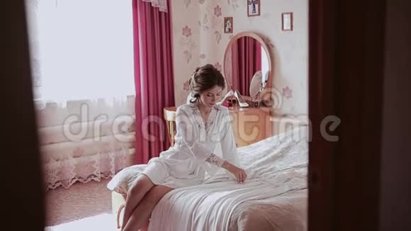 一个漂亮的女孩坐在床上摸一件连衣裙把它拉直视频的预览图