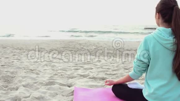 女人坐在沙滩上的瑜伽莲花姿势视频的预览图
