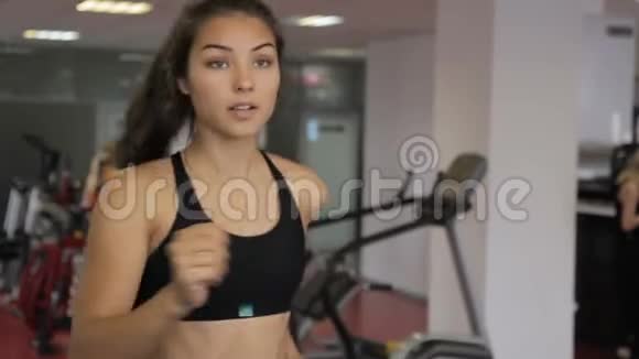 年轻女子在室内运动俱乐部跑步机上跑步视频的预览图