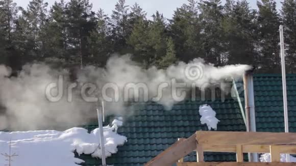 从森林屋顶屋上方的烟囱冒出的烟和蒸汽视频的预览图