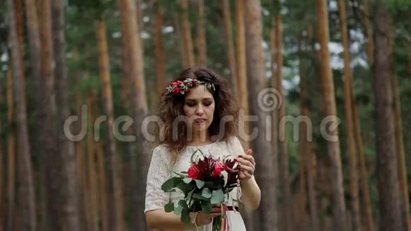 美丽的新娘穿着一件老式的连衣裙在夏天的森林里他头上戴着乌鸦的彩色鲜花视频的预览图