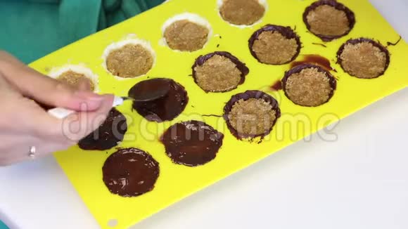 一个女人用压碎的杏仁覆盖融化的巧克力馅杏仁是有机硅形式的烹饪糖果巧克力釉视频的预览图