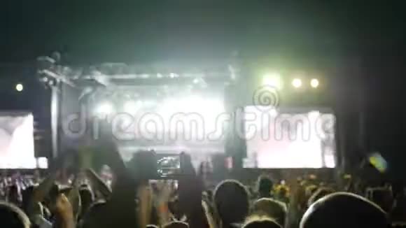 人们在音乐会上跳起来鼓掌歌迷们在音乐会上录制视频并用智能手机拍照视频的预览图