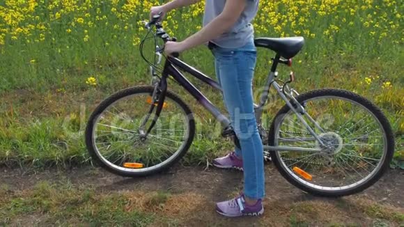 大自然中骑自行车的女孩一个女人在城外骑自行车健康的生活方式油菜田乡村公路视频的预览图