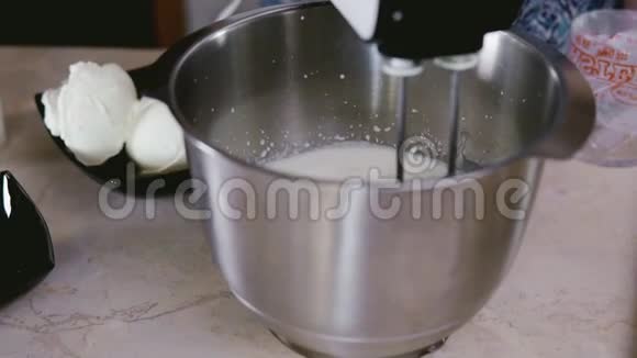 在搅拌机里搅拌奶油家庭主妇混合奶油做松饼近景视频的预览图
