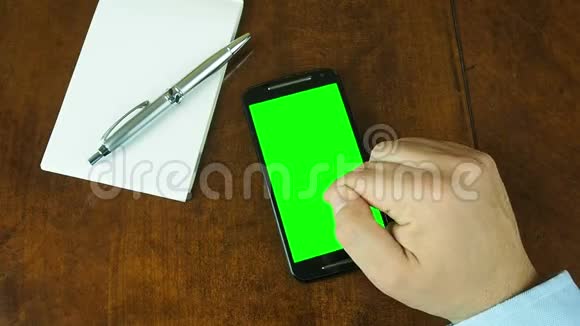 手在智能手机桌上的绿色屏幕上工作视频的预览图