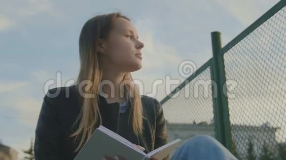 可爱的小女孩写日记坐在操场上黄昏的时候视频的预览图