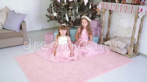 两个小女孩一起玩耍在圣诞树附近大笑视频的预览图