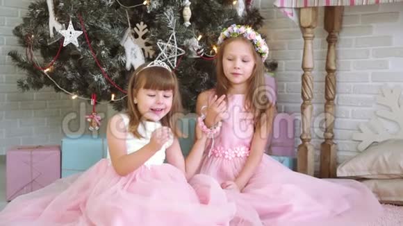 两个小女孩一起玩耍在圣诞树附近大笑视频的预览图