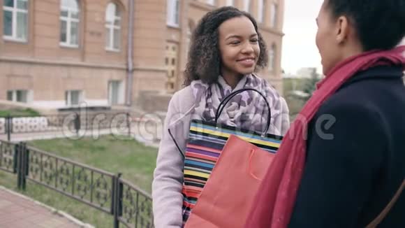两个年轻的非裔美国妇女在购物袋里互相分享她们的新购买有魅力的女孩说话视频的预览图