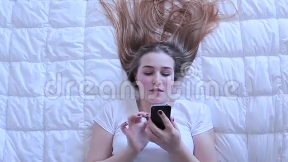 女孩在躺在床上的手机上输入信息视频的预览图