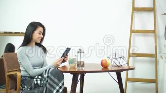 漂亮的女孩用平板电脑坐在家里舒适的椅子上视频的预览图
