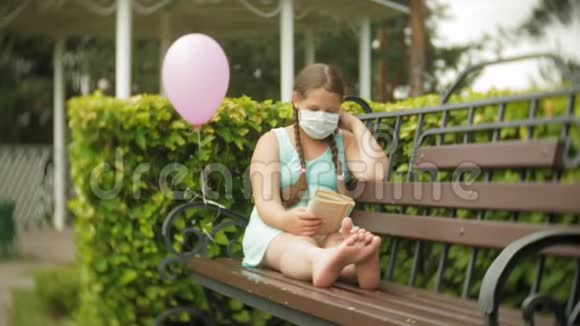 戴着呼吸器的可爱女孩在公园的长椅上看书视频的预览图