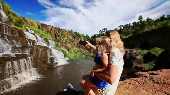 母亲紧紧抓住膝盖小女孩因瀑布而变得自私视频的预览图