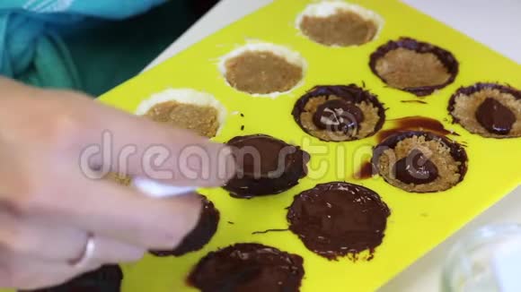 一个女人用压碎的杏仁覆盖融化的巧克力馅杏仁是有机硅形式的烹饪糖果白色和黑色的釉视频的预览图