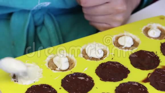 一个女人用压碎的杏仁覆盖融化的巧克力馅杏仁是有机硅形式的白色和黑色的烹饪糖果视频的预览图