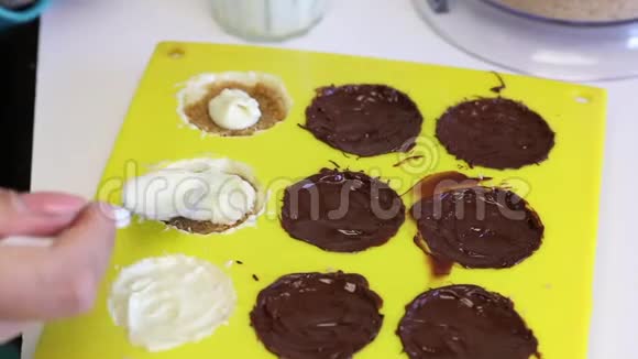 一个女人用压碎的杏仁覆盖融化的巧克力馅杏仁是有机硅形式的白色和黑色的烹饪糖果视频的预览图