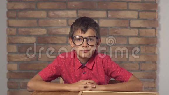 坐在书桌前的孩子拿着一张挂图上面写着红色砖墙上的公关字样视频的预览图