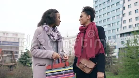 两个年轻的非裔美国妇女在购物袋里互相分享她们的新购买有魅力的女孩说话视频的预览图