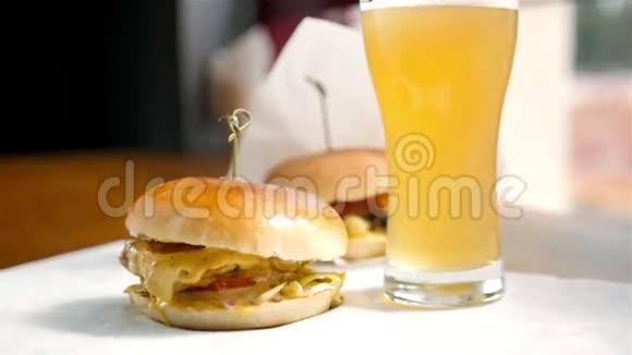 男人手拿一个汉堡里面有牛肉和蔬菜咖啡里有一杯啤酒视频的预览图