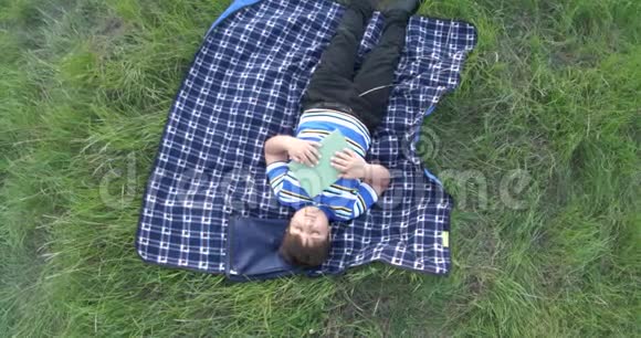 小男孩读完书后做梦他躺在草地上的地毯上视频的预览图