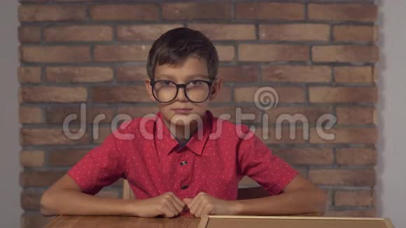 坐在书桌前的孩子拿着一张挂图背景是红砖墙上的刻字库视频的预览图