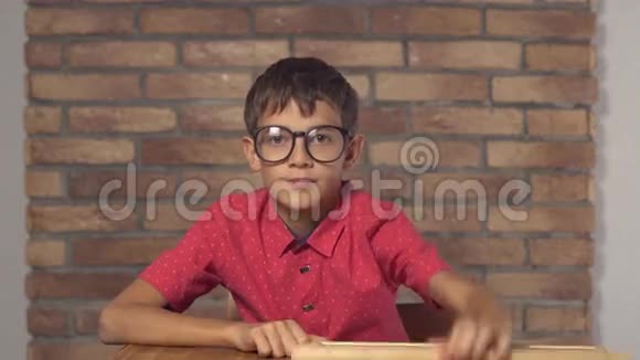 坐在书桌前的孩子拿着一张挂图上面写着红色砖墙上的刻字时间视频的预览图