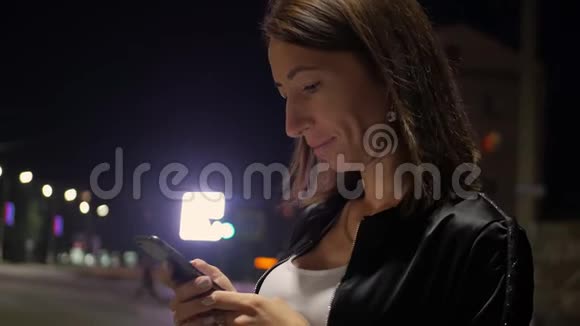 女孩晚上在城里用智能手机视频的预览图