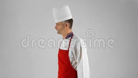 英俊的成年厨师转过身来他用小刀交叉双臂在灰色背景上点头视频的预览图