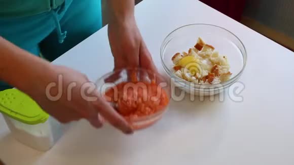 一个女人正在用鲑鱼做肉糜将切碎的鲑鱼肉加入一个装有鸡蛋和碎面包的容器中视频的预览图
