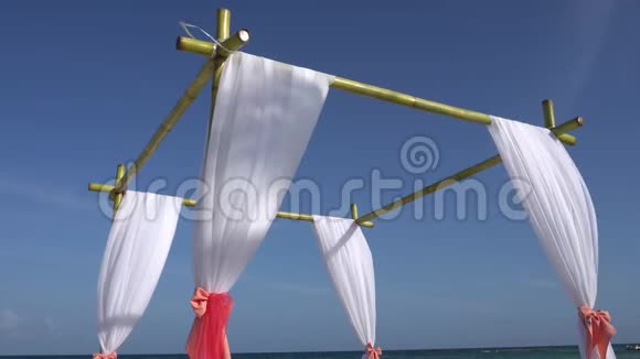 婚礼拱门装饰在热带海滩上的大型风力发展织物加勒比海绿松石水视频的预览图