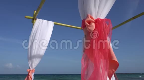 婚礼拱门装饰在热带海滩上的大型风力发展织物加勒比海绿松石水视频的预览图